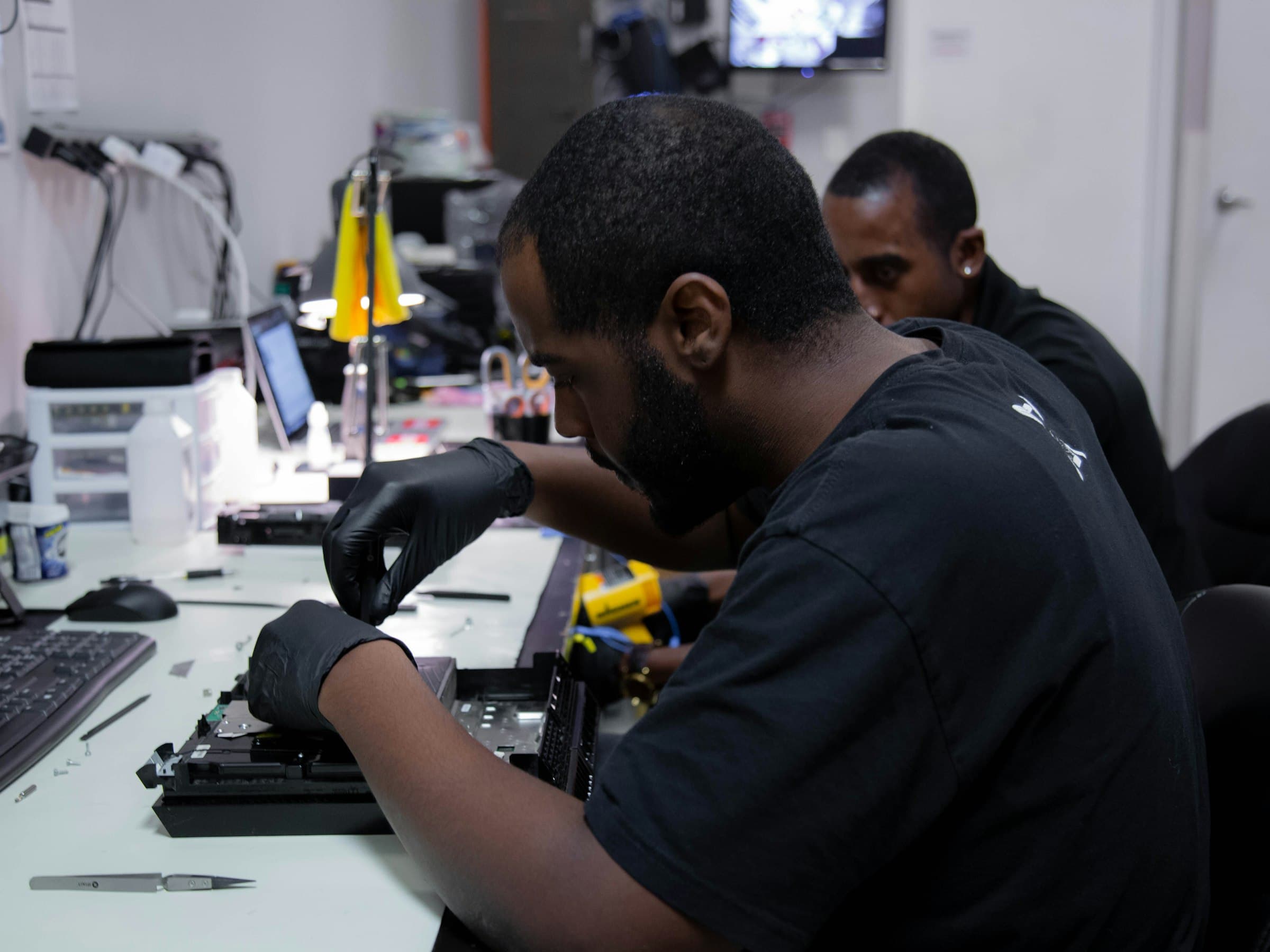 A technician repairing a laptop at a service bench